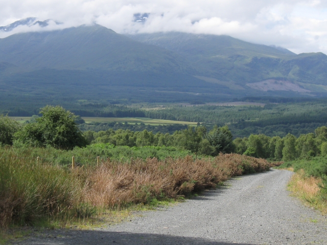 View down track: Aonach Mor and Beag with snow patches behind cloud